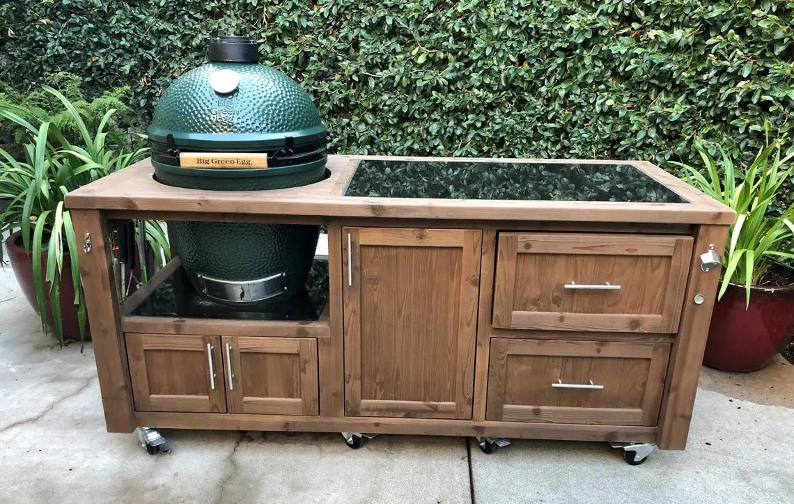 Big Green Egg grill cabinet stained in rich brown with a polished black granite countertop, featuring side bottle opener and sleek hardware.