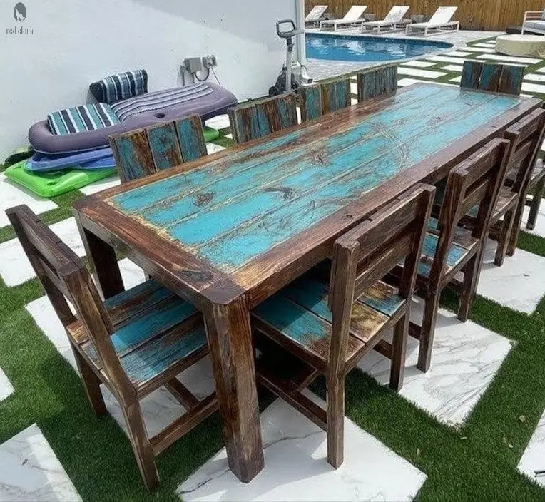 Close-up of handcrafted reclaimed wood dining table with teal finish, paired with custom rustic chairs for outdoor hosting