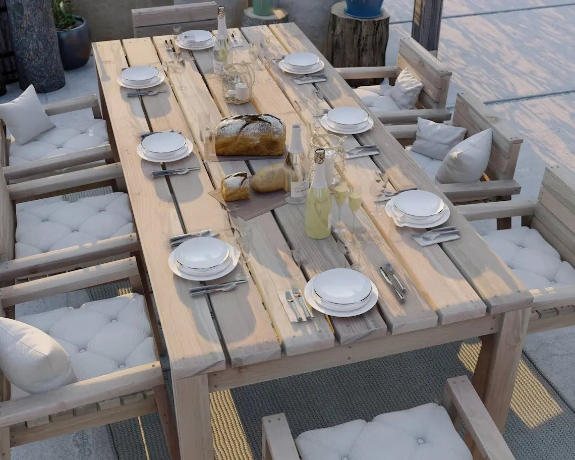 Solid wood dining table set with white-cushioned chairs, styled for outdoor entertaining with a natural farmhouse vibe