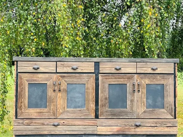 Front-facing view of reclaimed wood kitchen island with drawers and lower storage, set in front of tree backdrop – Red Cloak Wood Designs