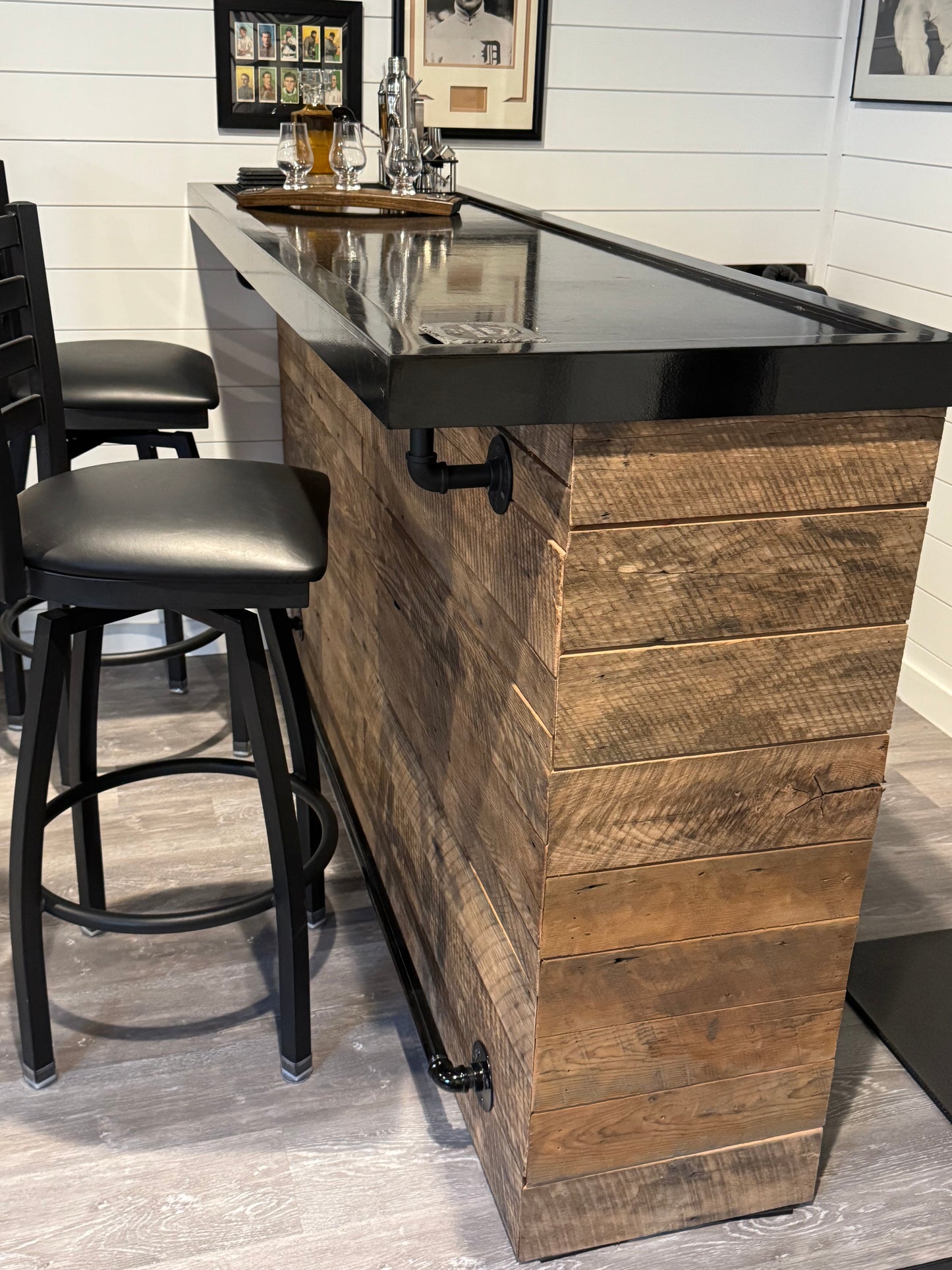 Indoor barnwood bar with black epoxy top and industrial foot rail, handcrafted by Red Cloak Wood Designs
