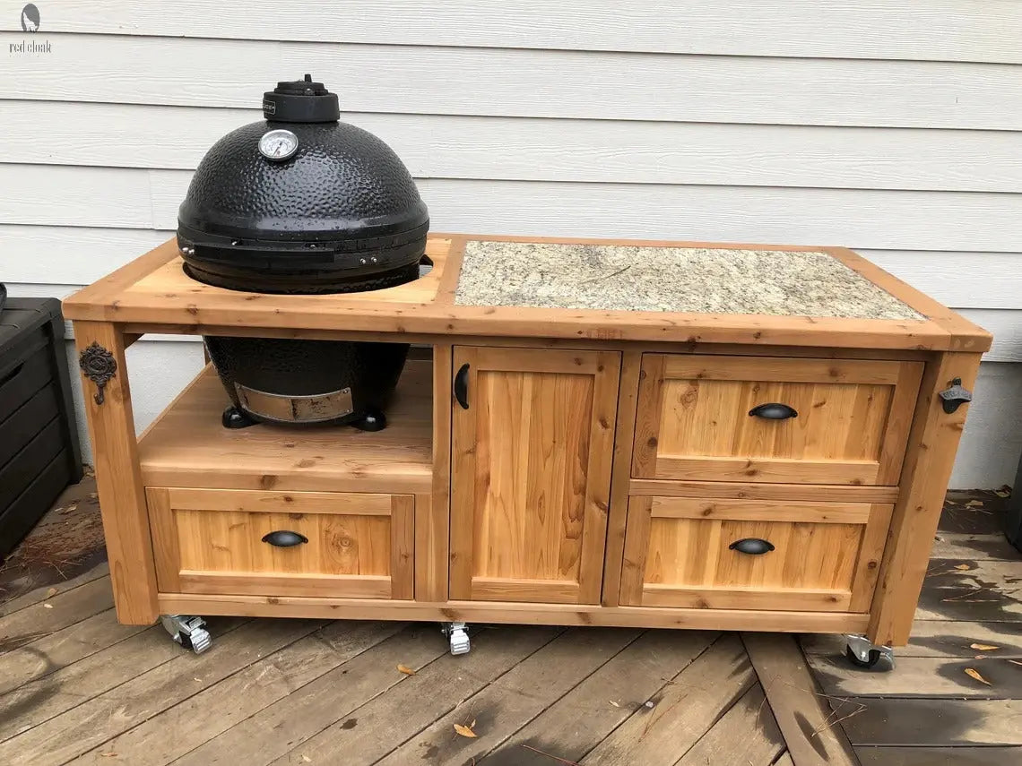 Kamado Joe smoker cart built from natural Western Red Cedar with granite countertop and lockable casters, shown on a wood deck.
