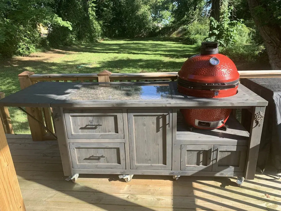 Gray-stained Kamado Joe grill cart with granite prep area, side shelf, and locking caster wheels, handcrafted for backyard BBQ use