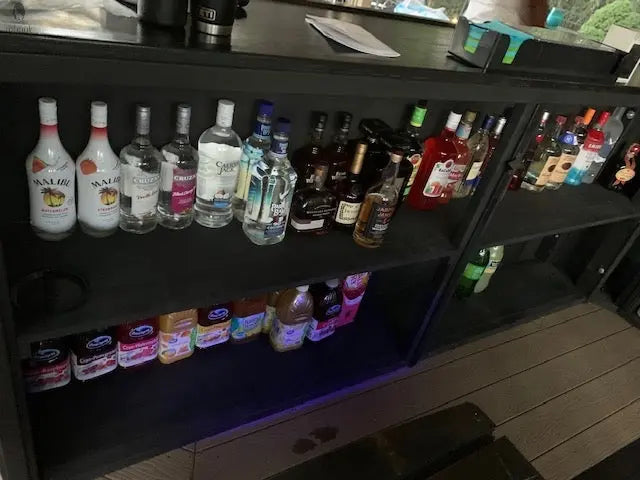Home bar furniture with open shelving stocked with liquor and mixers, built from reclaimed barnwood for indoor use
