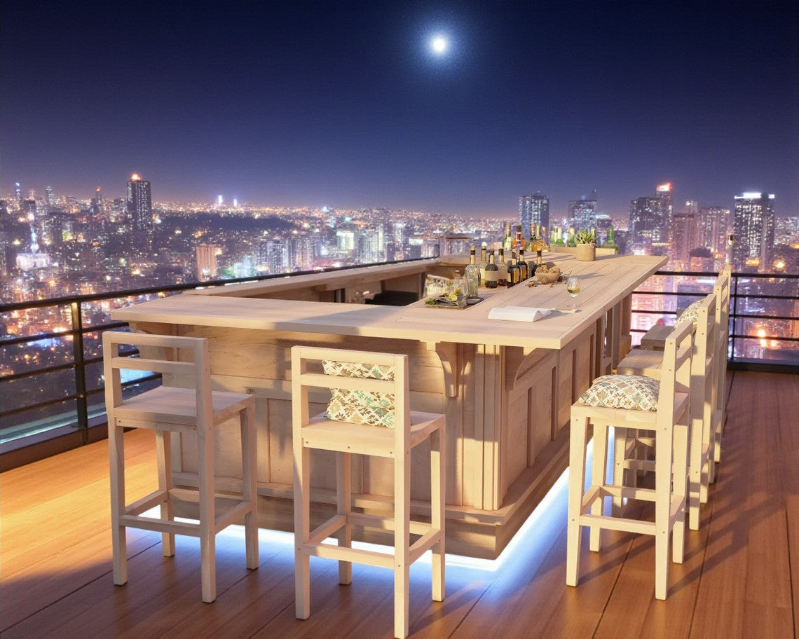 U-shaped bar by Red Cloak Home on a rooftop deck with LED base lighting and panoramic city skyline at night