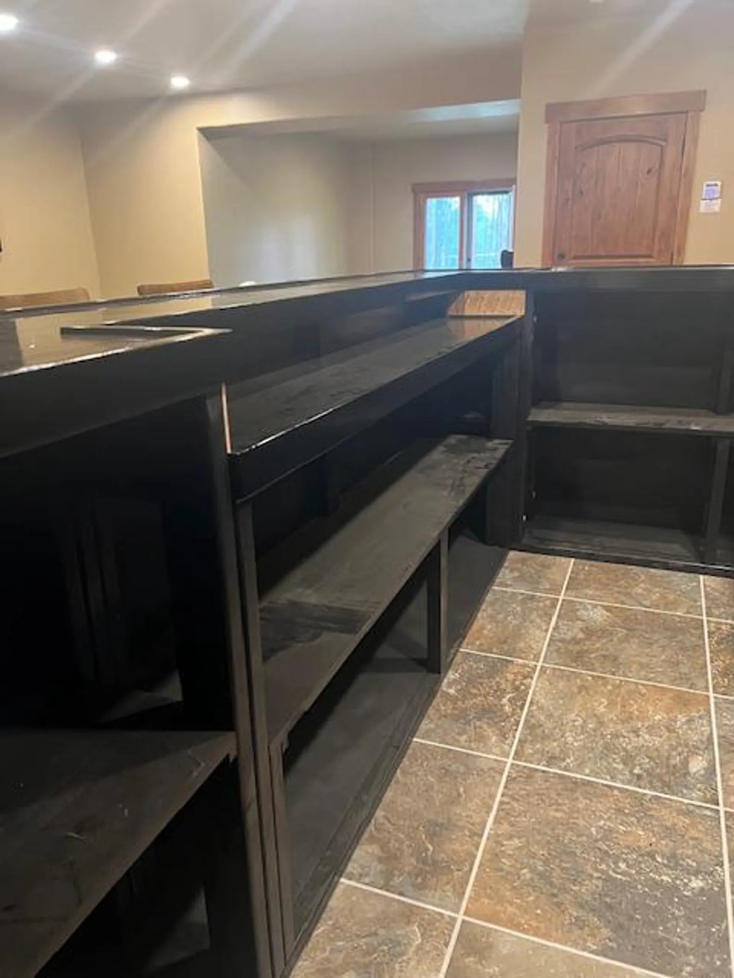 Interior shelving detail inside the custom black U-shaped bar, showing ample storage beneath high-gloss black top.