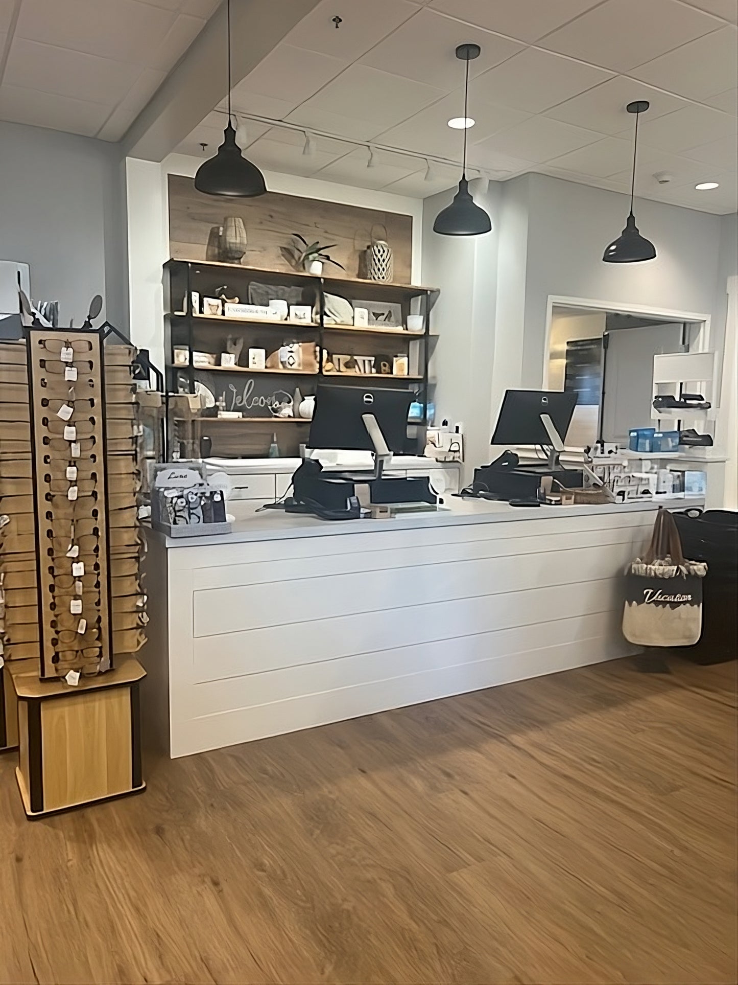 Upscaled image of full white shiplap checkout counter with warm wood floors and pendant lighting, handcrafted by Red Cloak Wood Designs
