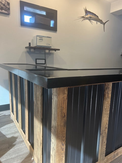 L-shaped commercial counter with black metal panels and wood framing, custom retail checkout counter with glossy sealed top in modern business space, USA