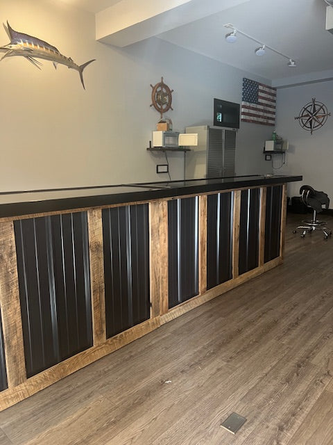 L-shaped commercial counter in retail space with wood framing and black metal panels, custom checkout counter with sealed top and open service layout, USA