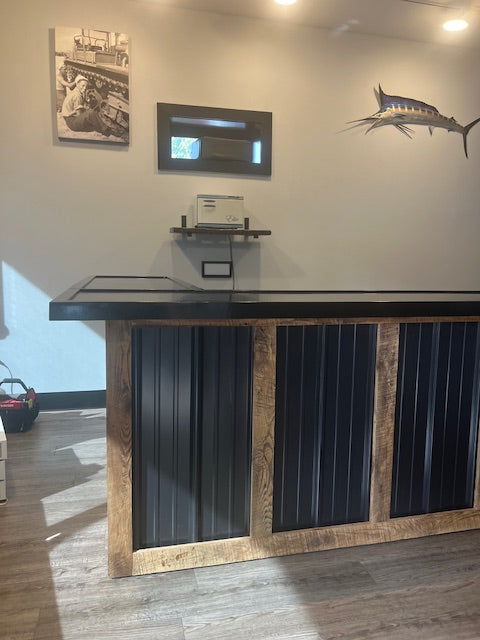 corner view of L-shaped commercial counter with wood frame and black metal panels, custom retail checkout counter with overhang and sealed top, USA