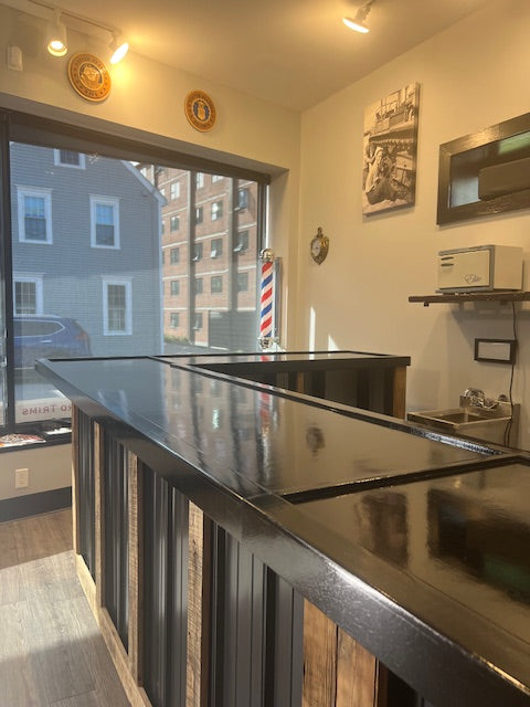 L-shaped commercial counter with glossy sealed countertop near storefront window, custom retail checkout counter with wood frame and metal panels, USA