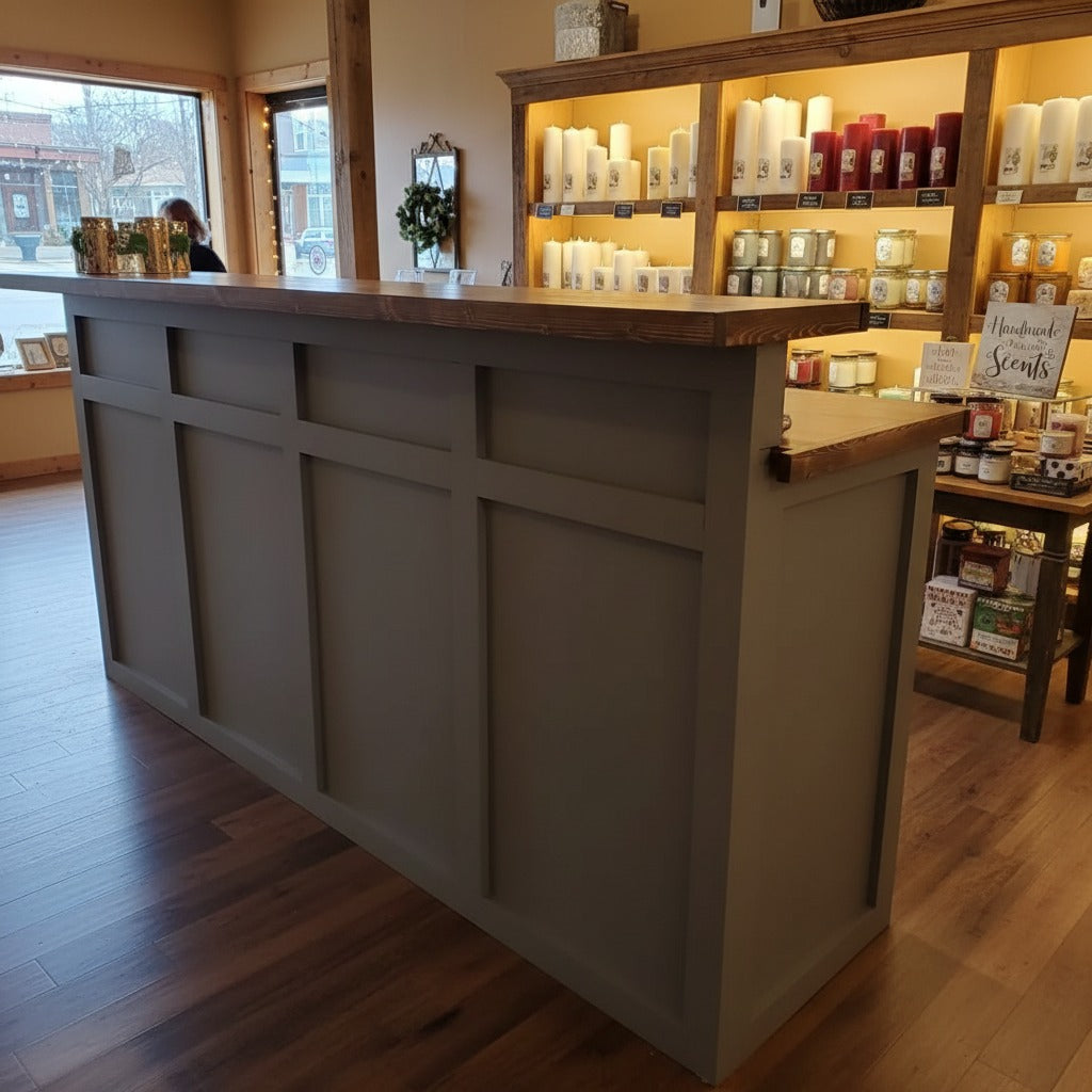 Custom gray retail checkout counter with paneled front and wood countertop in a candle and gift shop. Handmade by Red Cloak Home