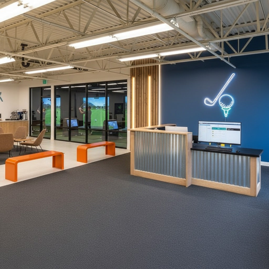 Wide view of a custom commercial reception desk with return in a modern indoor golf facility. Handmade by Red Clock Home