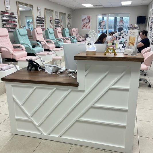 White split-level reception desk with geometric paneling and wood countertops inside a modern nail salon. Handmade by Red Cloak Home