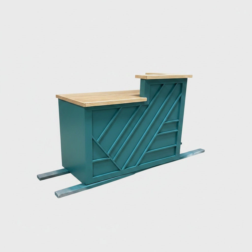 Teal split-level reception desk with geometric front trim, natural wood work surfaces, and raised customer ledge. Handmade by Red Cloak Home