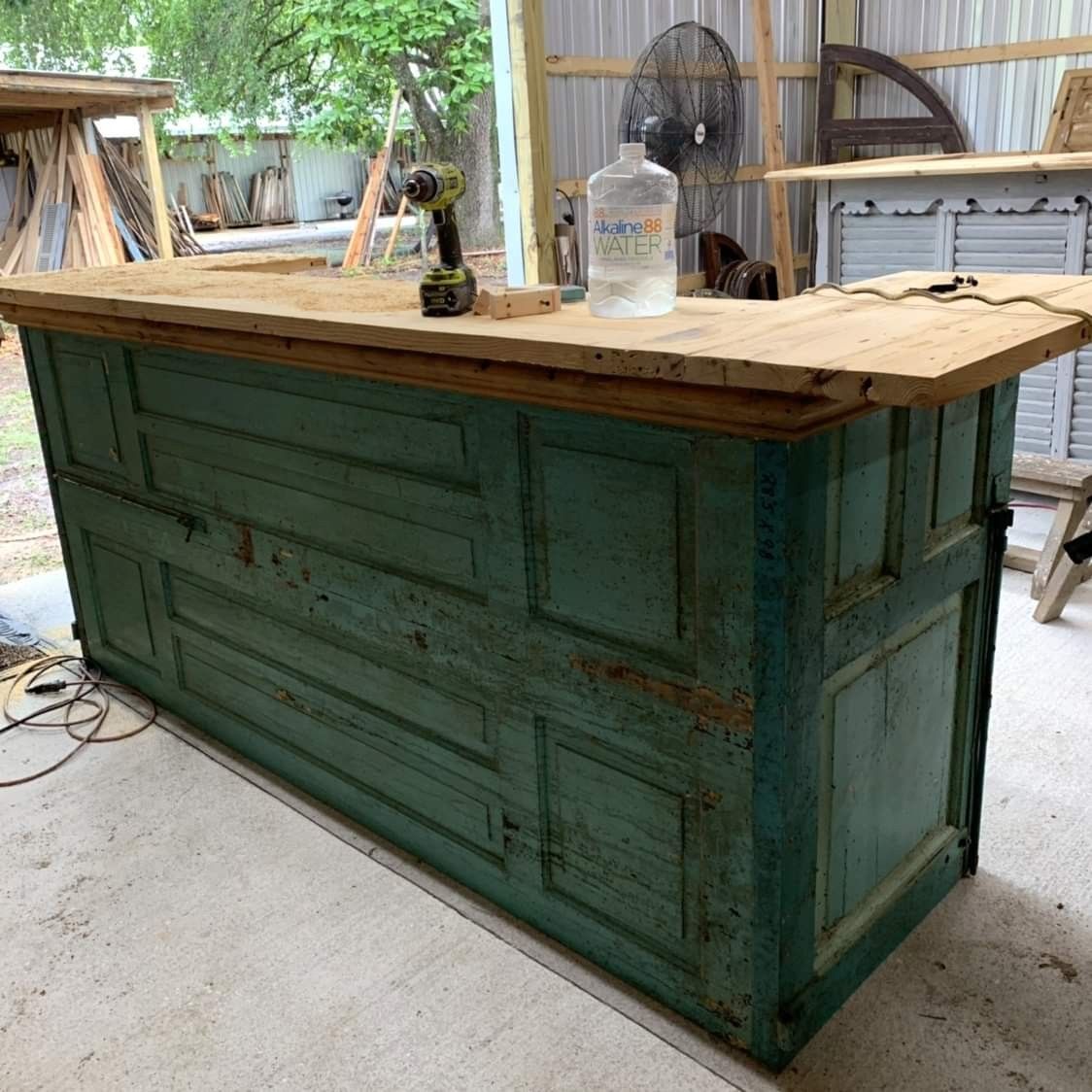 Turquoise vintage door checkout counter with unfinished reclaimed wood countertop in the workshop. Handmade by Red Cloak Home