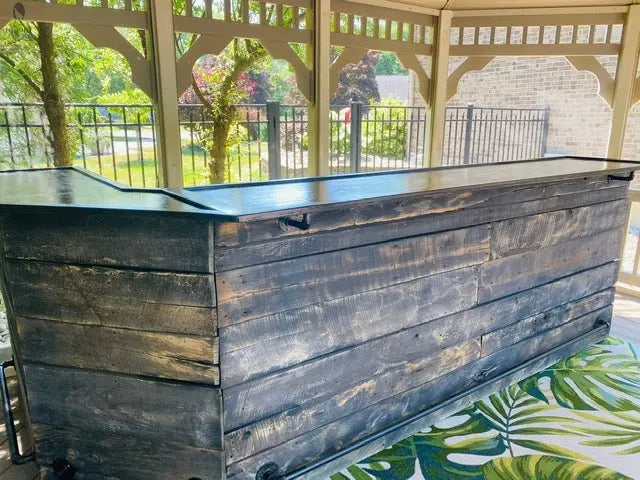 Backside of custom L-shaped outdoor bar with open counter and storage and metal foot rail, designed for patio entertaining