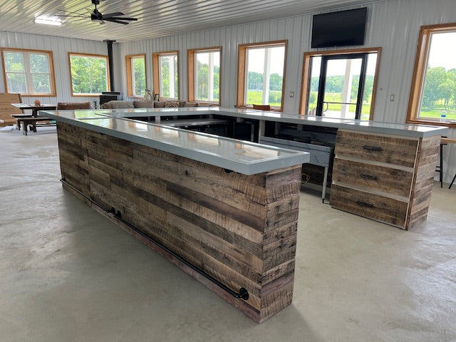 Large U-shaped bar built from reclaimed wood with white countertop, shown in bright indoor space by Red Cloak Home