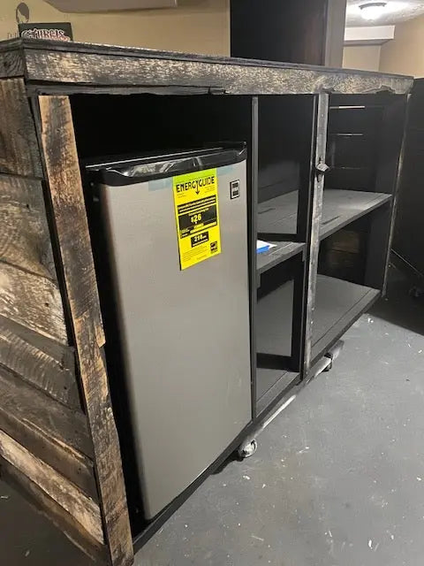 Close-up of fridge installed inside reclaimed barnwood bar with shelves