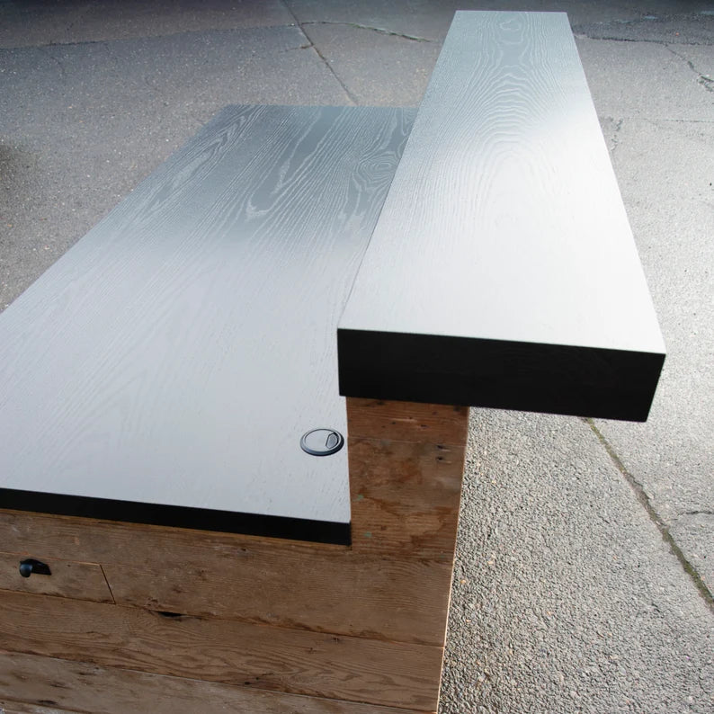 Close-up of the black wood work surface and raised transaction ledge on a custom reclaimed wood reception desk. Handmade by Red Cloak Home