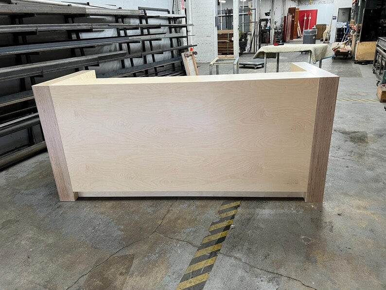 Front view of a custom birch reception desk with a clean modern design and raised transaction counter. Handmade by Red Cloak Home