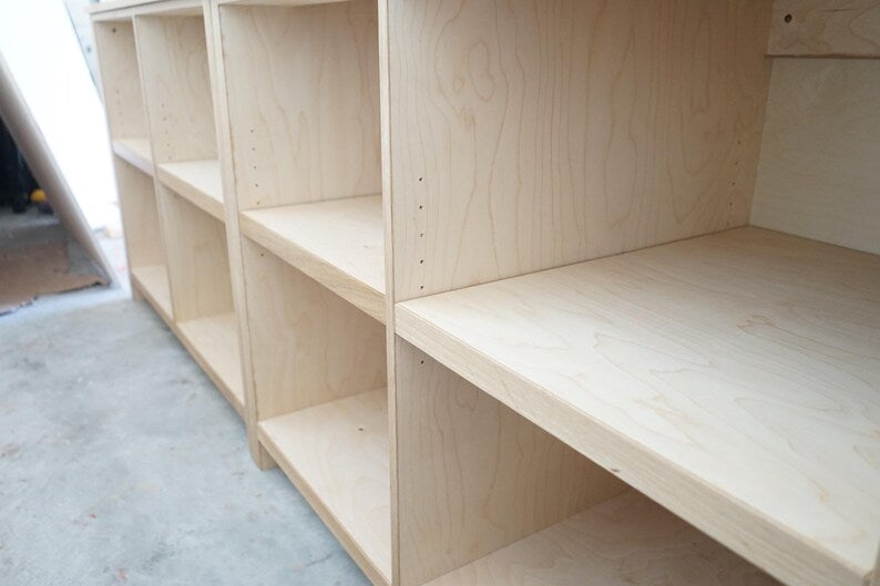 Employee-side shelving inside a custom fluted wood checkout counter for retail storage. Handmade by Red Cloak Home
