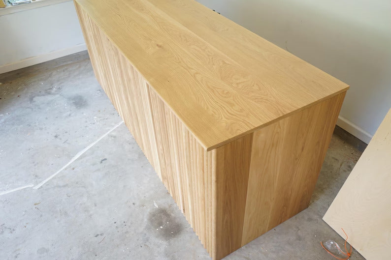 Angled top view of a custom wood cash wrap counter with fluted front and natural countertop. Handmade by Red Cloak Home