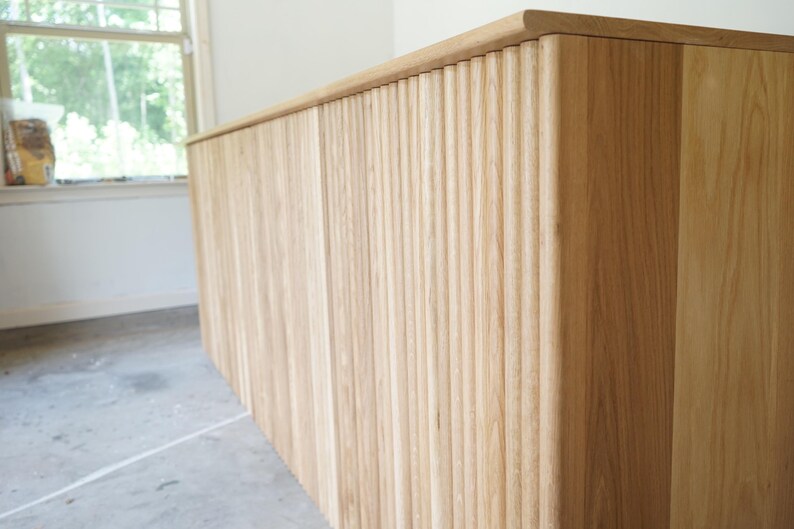 Close-up of the rounded corner and vertical wood slats on a fluted retail cash wrap counter. Handmade by Red Cloak Home