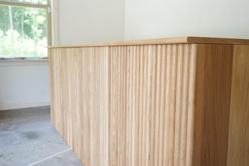Detailed angled view of the natural wood countertop and fluted front of a custom checkout counter. Handmade by Red Cloak Home