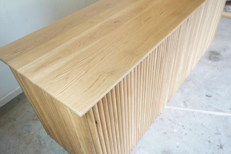 Close-up of the natural wood worktop and rounded fluted front on a custom commercial checkout counter. Handmade by Red Cloak Home