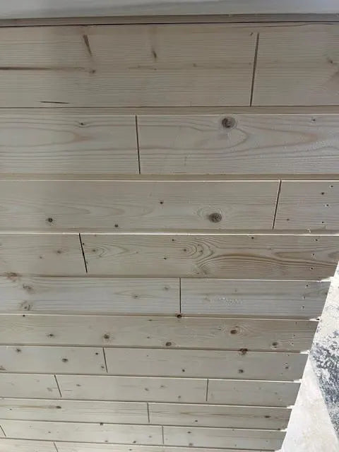Light natural wood planks arranged horizontally, showing visible grain, knots, and screw fasteners, photographed close up.