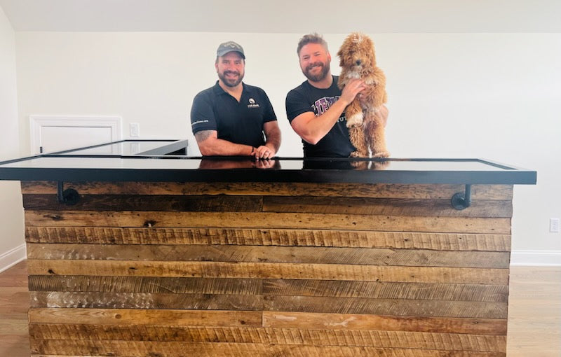 Country music artist Jimmy Charles with Red Cloak Home installer standing behind custom reclaimed barn wood bar in Nashville home