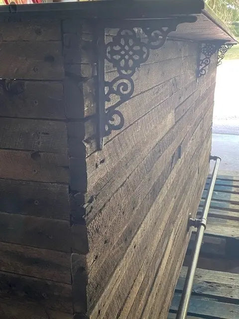 Decorative iron bracket with diagonal foot rail installed on rustic wood bar corner