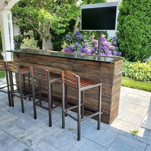 Custom outdoor barnwood bar with diagonal metal foot rail mounted on stone patio