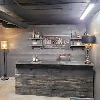 Reclaimed wood bar with upper shelf and industrial lighting, custom indoor speakeasy setup by Red Cloak