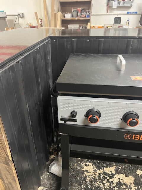 Close-up of Blackstone Bronco griddle installed in Red Cloak Home’s handmade wood bar, showing tight fit and metal heat shield lining.