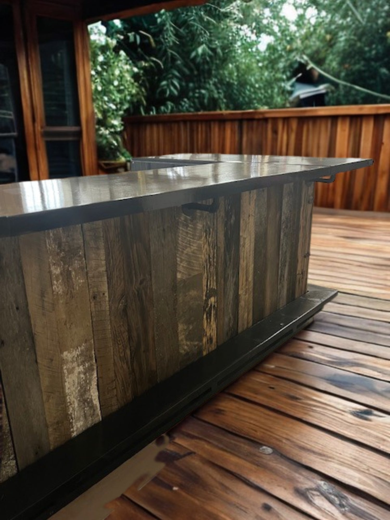Outdoor view of handmade wood Blackstone bar by Red Cloak Home, shown installed on a covered deck with rustic reclaimed wood and full footrail.