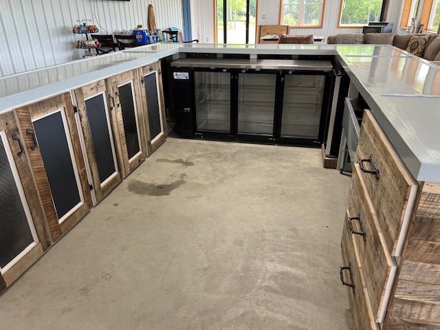 Interior view of U-shaped wood bar showing storage drawers, cabinet doors, and built-in cooler by Red Cloak Home