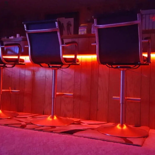 LED strip lighting glowing red under home bar counter with barstools, custom setup from Red Cloak Wood Designs
