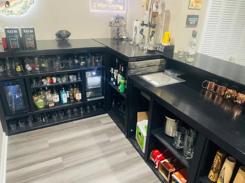 Inside view of custom L shaped bar with glassware shelves, mini fridge, wet sink, and liquor tap setup by Red Cloak Wood Designs